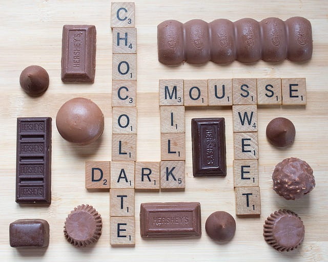 Différentes sortes de chocolats mélangées à des lettres de scrabble.